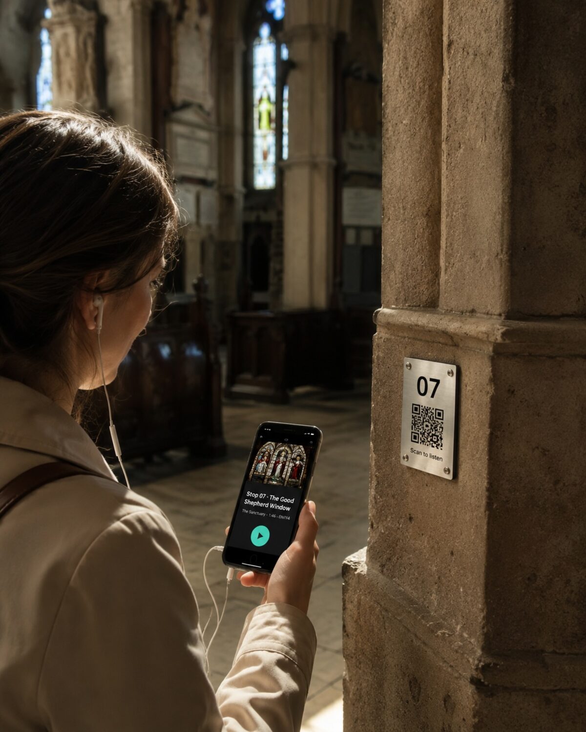 A visitor with wired earbuds stands in a church bathed in stained-glass light, holding a phone showing the Wexplo audio guide for "Stop 07 · The Good Shepherd Window, The Sanctuary." A brushed brass plate numbered 07 with a QR code labelled "Scan to listen" is mounted on the stone column beside her.